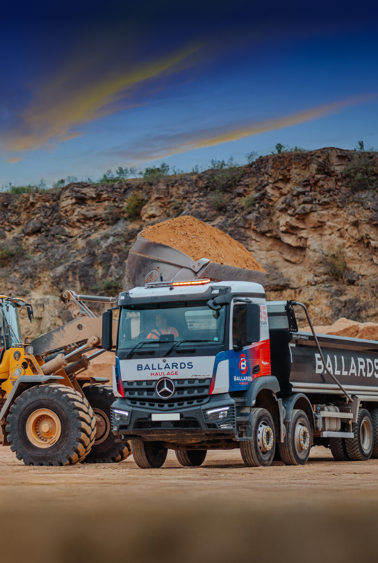 A truck tipping gravel from a quarry into a Ballards Tipper Truck