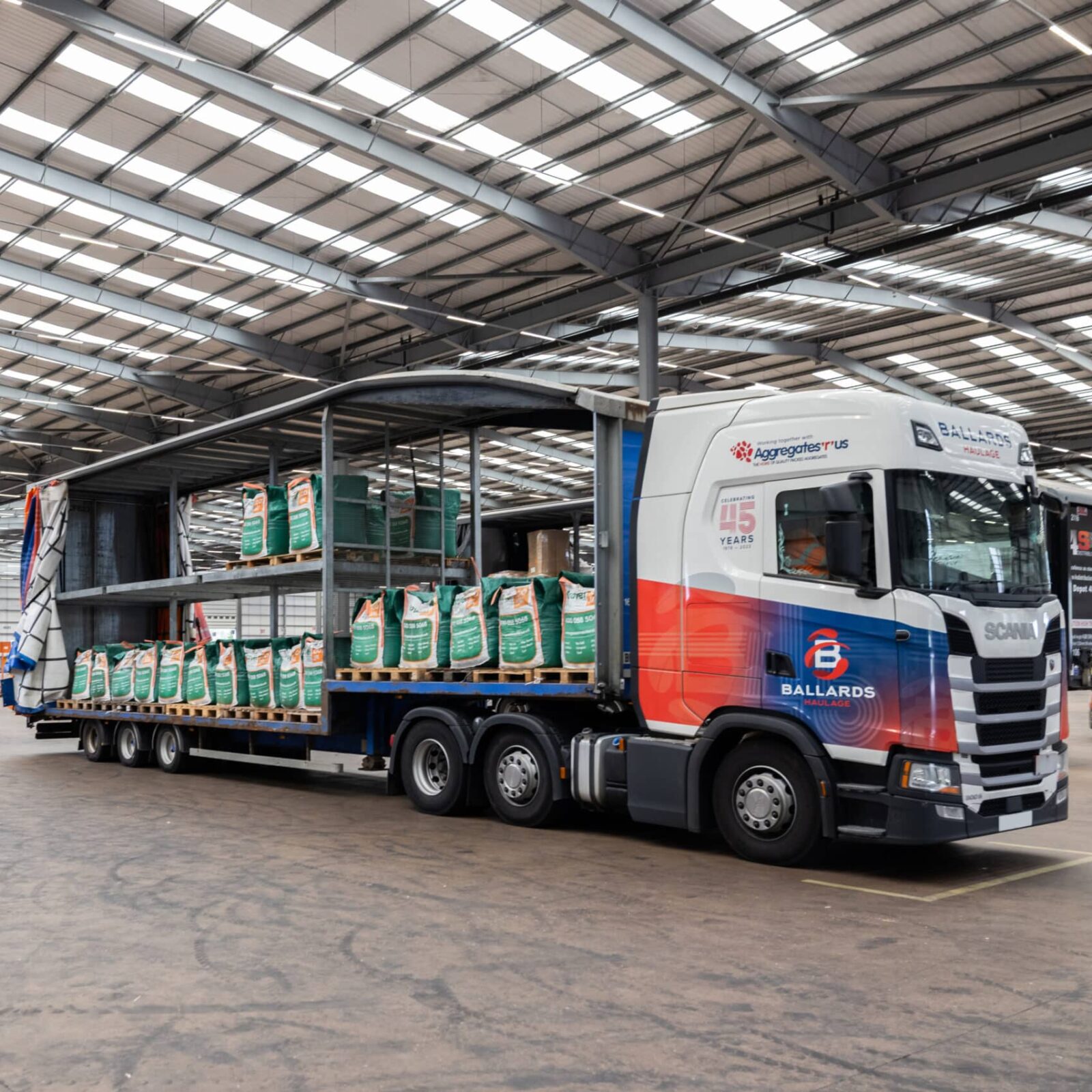 Ballards curtain sider trailer in warehouse loading areas with curtsin open showing trailer interior with bags of aggregate
